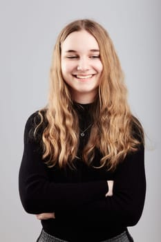 Portrait of pretty cheerful young woman holding arms crossed standing over a grey plain background