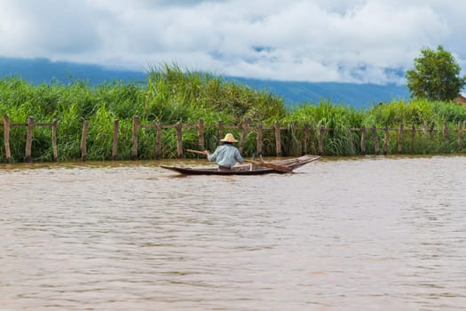 The Inle Lake. Myanmar: 17 August 2020: Fisherman rowing boat on Inle Lake, Myanmar. Inle Lake is famous for its floating villages and gardens.