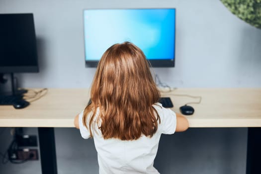 Child learning to use technology in classroom at primary school. Schoolgirl using computer on elementary computer science class. Smart little girl learning programming and coding at school. Engaged child solving riddles on personal computer. Back to school