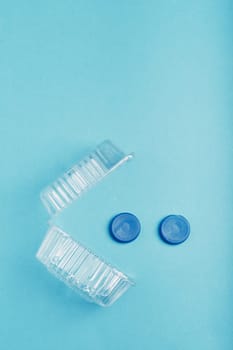 Plastic packaging and bottle caps over blue background. Collecting plastic waste to recycling. Concept of plastic pollution and too many plastic waste. Copy space for text