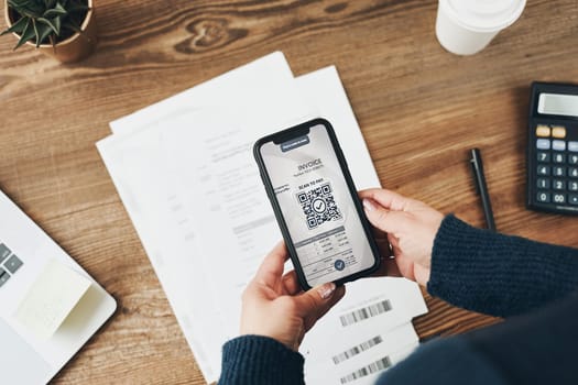 Woman paying invoice scanning QR code from document using fast secure payment system and smartphone QR scanner. Business woman paying bills using express payment technology. Female using mobile phone and laptop. Paying expenses online