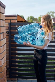 Young woman throwing out empty used plastic water bottles into trash bin. Collecting plastic waste to recycling. Concept of plastic pollution and too many plastic waste. Environmental issue