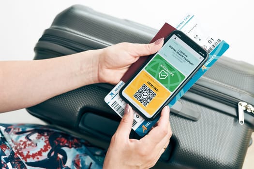 Digital covid certificate. Covid negative rapid digital test pass. Woman passenger holding digital medical pass on her mobile phone, passport and airplane ticket. Traveler showing digital covid test result as medical pass for travel during covid-19 pandemic