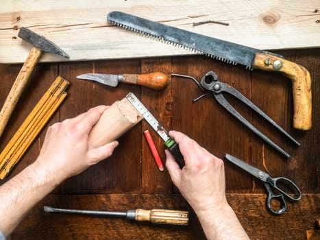 Hands of man measuring piece of wood using tape measure