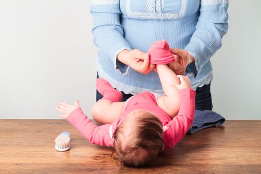 Mom putting the socks on her little baby girl
