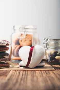 Gingerbread cookies, candies, cakes, sweets in jars on wooden table. Portrait orientation