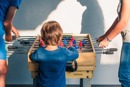 Young teenager boy playing table football with another player. Young people having fun, spending time together