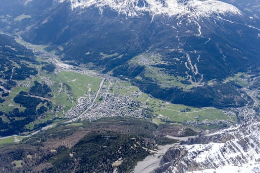 aerial landscape, from a glider plane, of Bormio touristic mountain village and its valley, shot from above Reit peak in bright late spring light, Sondrio, Italy
