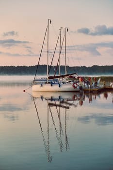 Yachts and boats moored in a harbour at sunrise. Candid people, real moments, authentic situations