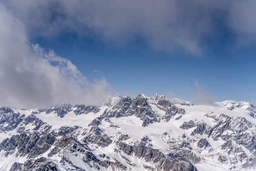 aerial landscape, from a glider plane, of Bernina summit looming out of clouds, shot from south in bright late spring light, Sondrio, Italy