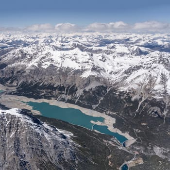 aerial landscape, from a glider plane, of big dam at Cancano lake in Fraele valley, shot from south west in bright late spring light, Sondrio, Italy