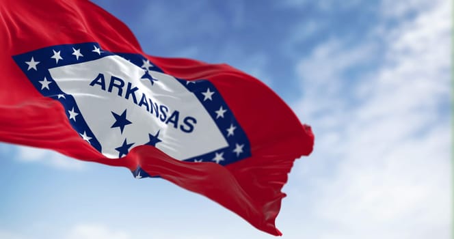 Arkansas state flag waving in the wind on a clear day. Red field with blue-bordered white diamond. 29 stars and ARKANSAS in blue. 3d illustration render. Fluttering fabric. Selective focus