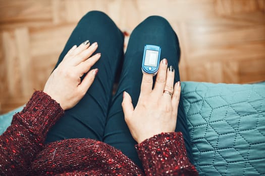 Woman measuring the degree of oxygen saturation of the blood and heart rate at home using pulse oximeter. Home treatment of virus. Checking health condition. Coronavirus pandemic. Covid-19 outbreak