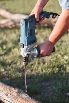 Man drilling hole in timber while working in garden