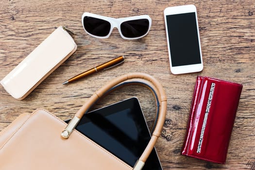 Smartphone sunglasses wallet and other things pulled out of handbag put on a table