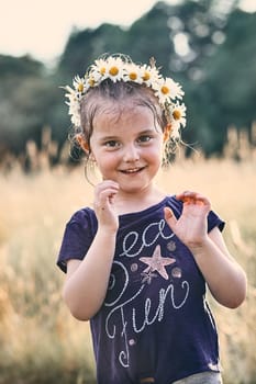 Little girl wearing a coronet of wild flowers on her head. Candid people, real moments, authentic situations