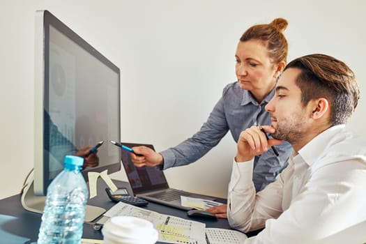 Business colleagues discussing financial data working together in office. People entrepreneurs working with charts and tables on computer. Two people working together. Workmates talking about project