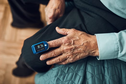 Senior man measuring the degree of oxygen saturation of the blood and heart rate at home using pulse oximeter. Home treatment of virus. Checking health condition. Coronavirus pandemic. Covid-19 outbreak