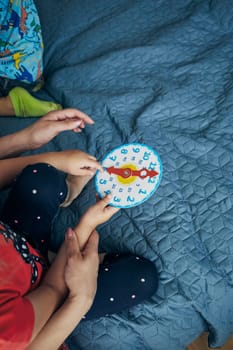 Kids learning how to tell time from clock and set the hands in the correct position. Teaching preschoolers tell time. Candid people, real moments, authentic situations