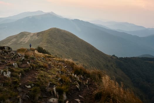 Hiking in mountains. Mountain landscape. Scenic view of mountain peaks, slopes, hills and valleys covered with grass and trees. Panoramic view. Natural scenery. Beautiful background