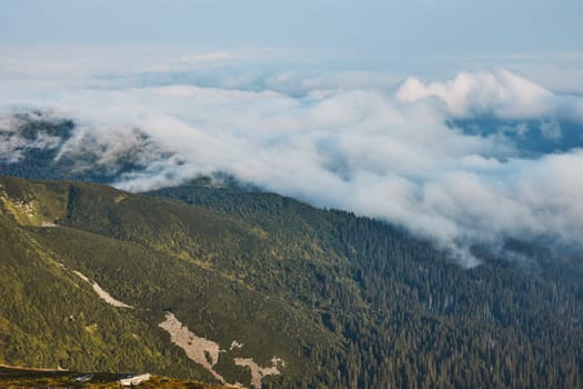 Mountain landscape. Scenic view of mountain peaks, slopes, hills and valleys covered with foggy slopes and valleys. Panoramic view. Natural scenery. Beautiful background