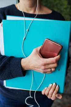 Woman working remotely doing job during call conversation on phone from home. Woman holding smartphone and documents in binder using headphones
