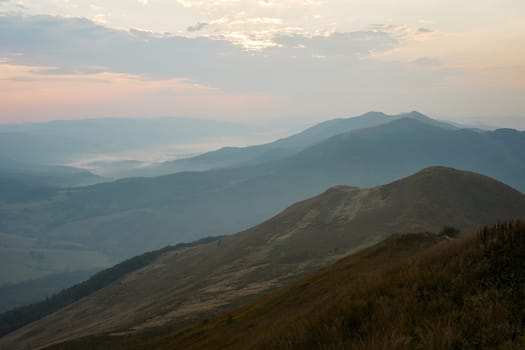 Mountain landscape. Scenic view of mountain peaks, slopes, hills and valleys covered with foggy slopes and valleys. Panoramic view. Natural scenery. Beautiful background
