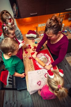 Baking Christmas cookies. Christmas gingerbread cookies in many shapes decorated with colorful frosting, sprinkle, icing, chocolate coating, toppers, put on table. Baking traditional cookies. Family celebrating Christmas. Baking at home. Baked sweet cookies. Coating with frostings. Colouring cookies. Decorating baked cookies. Decoration and design of food. Flat top-down composition. Sweet dessert food. Putting a frost, frosting gingerbread. Shot from above