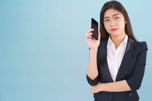 Young women in suit holding her phone standing against blue background
