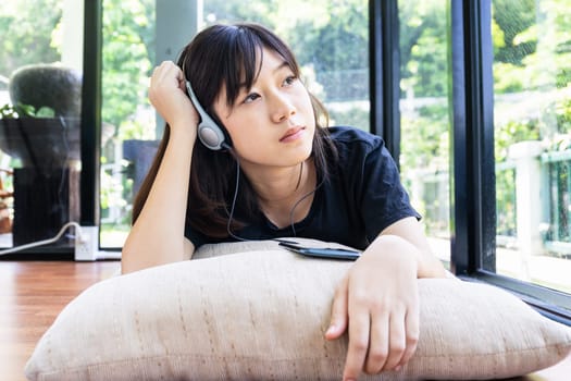 Teenage girl with headphones and listening to music from mobile phone at home