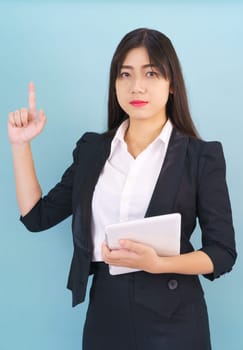 Young women standing in suit holding her digital tablet computor against blue background