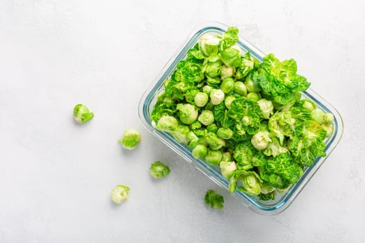 Fresh organic green brussels sprouts and small winter cabbage vegetable in glass container, ready to freeze