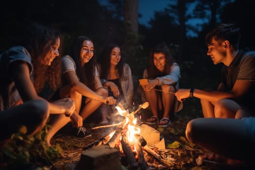 A group of friends sit around a campfire, roasting marshmallows as the night sky deepens around them. The scene is warm and cozy, with a golden hour quality to the light. This scene can evoke feelings of cheerfulness, playfulness, and nostalgia for summertime fun. (generative AI)