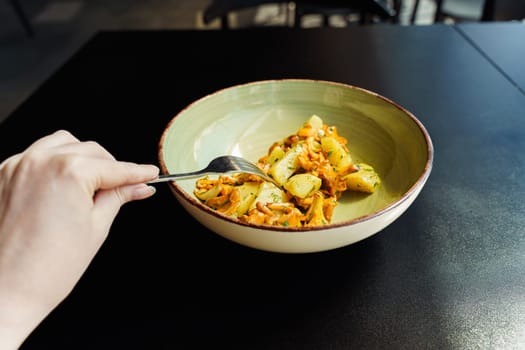 A woman dines on a fresh, vegetarian seasonal lunch. Fried wild mushrooms, chanterelles with boiled potatoes and herbs.