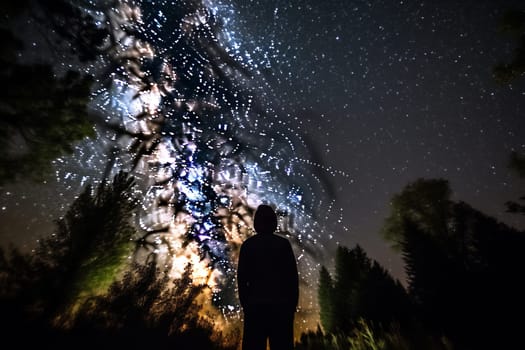 A person gazes up at the wonder of the night sky, contemplating the vastness and mystery of the cosmos. The celestial beauty of the stars and the peaceful surroundings of the outdoors create a sense of awe and introspection. This scene can evoke feelings of wonder, reflection, and a connection to something greater than oneself. (generative AI)