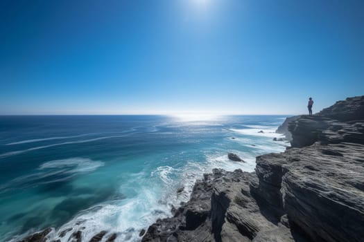 The person stands at the edge of the rocky cliff, staring out into the endless expanse of blue ocean and sky. The beauty and majesty of the natural world are on full display, with the vastness of the horizon dwarfing all else. This scene inspires a sense of awe and wonder, with a peaceful and reflective quality that is unmatched. (generative AI)