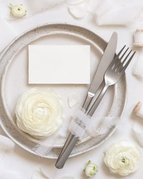Wedding table setting with card near cream roses and white silk ribbons top view, mockup. Romantic scene with horizontal table place card and pastel flowers. Valentines, Spring or Mothers day concept