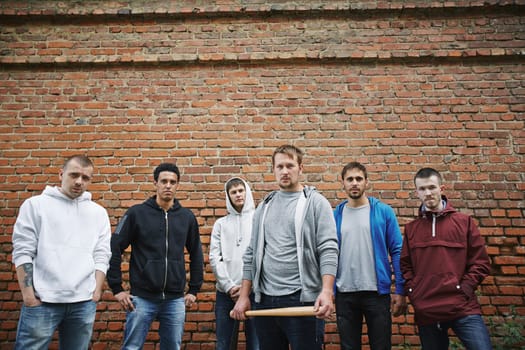 Group of hooligans or rappers on background of brick wall