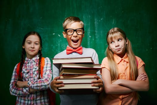 Ecstatic pupil with books standing between two schoolmates