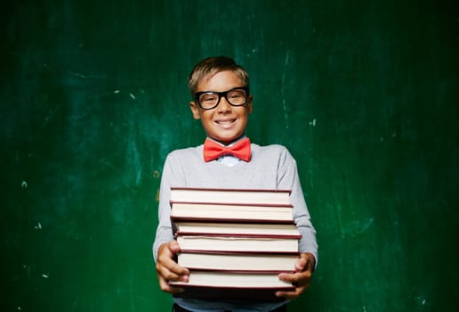Happy schoolboy with stack of books looking at camera