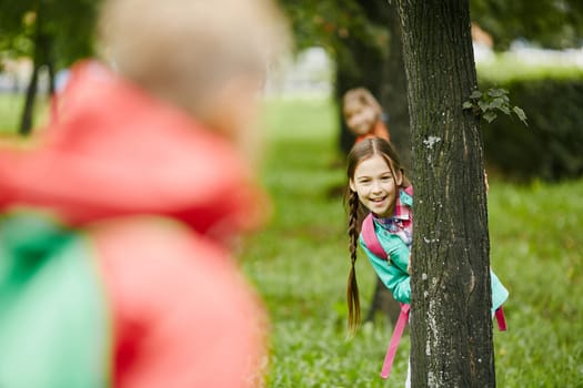 Little girl looking at camera out of tree trunk