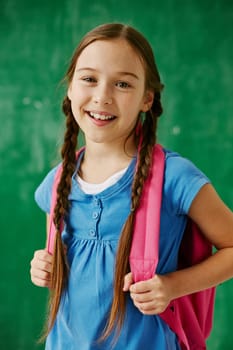 Cheerful schoolgirl with backpack looking at camera