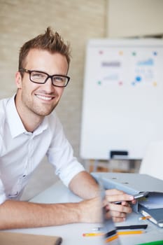 Smiling businessman in eyeglasses looking at camera in office