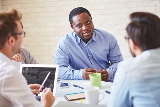 Serious manager of African ethnicity talking to colleagues