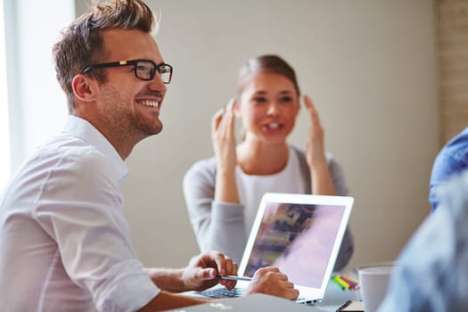Cheerful businessman in eyeglasses looking at colleague with smile