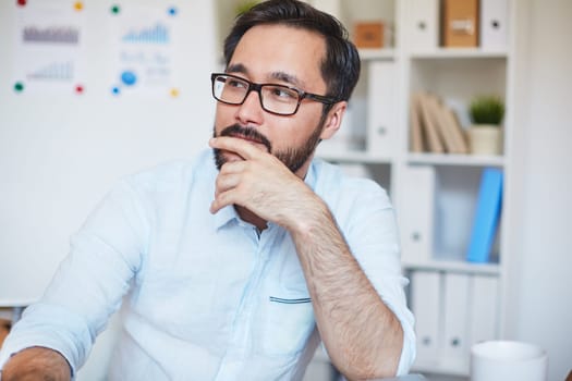 Pensive businessman in eyeglasses sitting in office