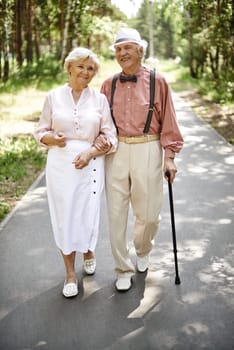 Affectionate seniors in smart casual going down park road