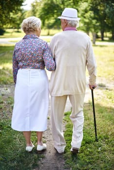 Rear view of senior couple in smart casual spending time in park