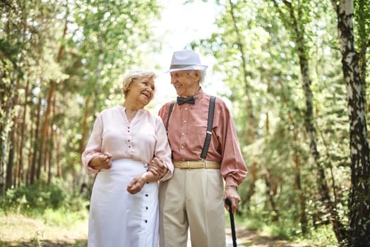 Affectionate seniors in smart casual talking while chilling out in park