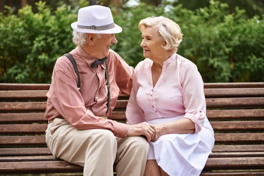Romantic seniors in smart casual relaxing in park and talking